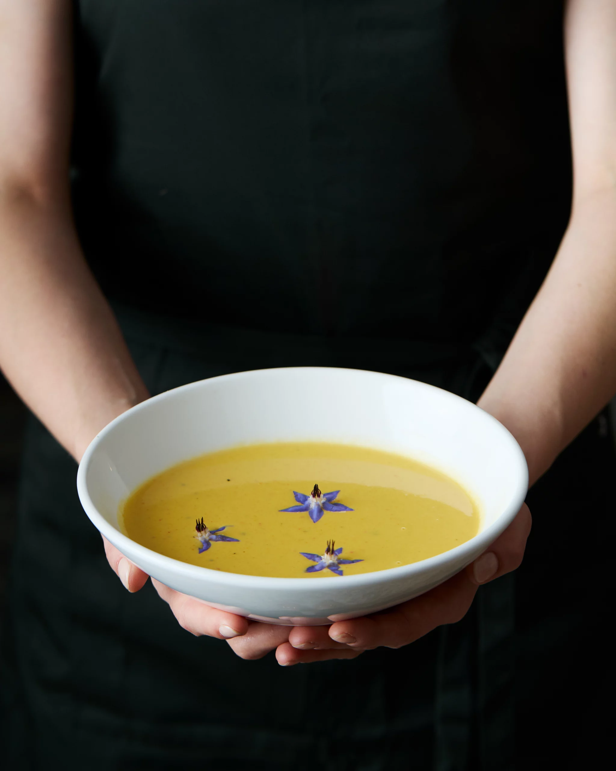 Foodfotografie mit Kürbissuppe angerichtet im traditionellen Restaurant von der Servicekraft. 
